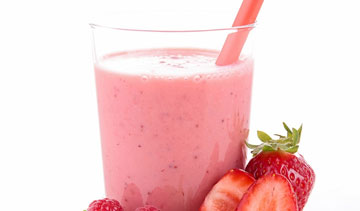 A pink smoothie with a straw and fresh berries.