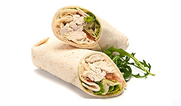 Chicken wrap sandwich cut in half with fresh greens.