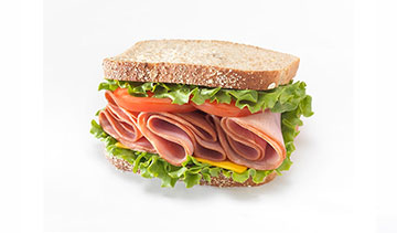 A sandwich with ham, lettuce, and whole wheat bread.