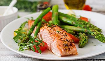Grilled salmon with asparagus and fresh salad on a white plate.