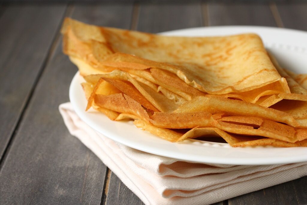 Stack of golden crepes on a white cloth.